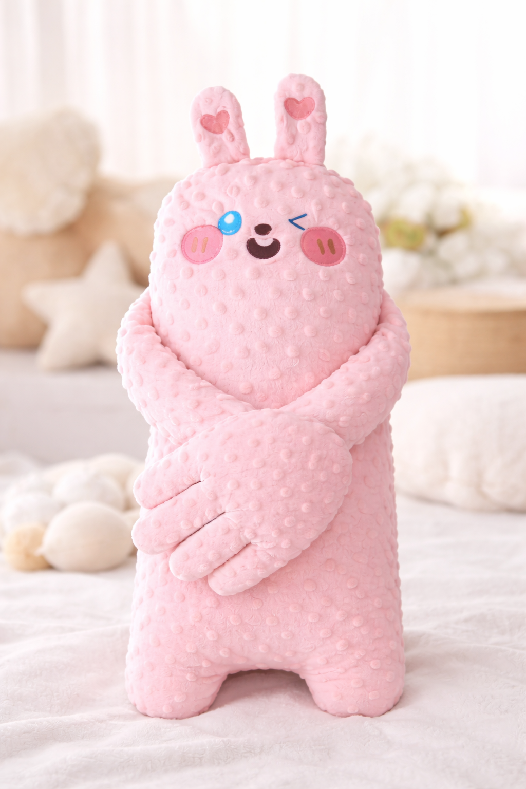 Pink plush toy with a cartoon face on a soft surface
